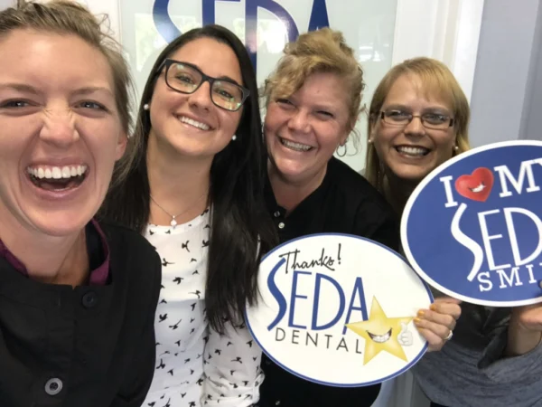 Smiling group holding dental signs.